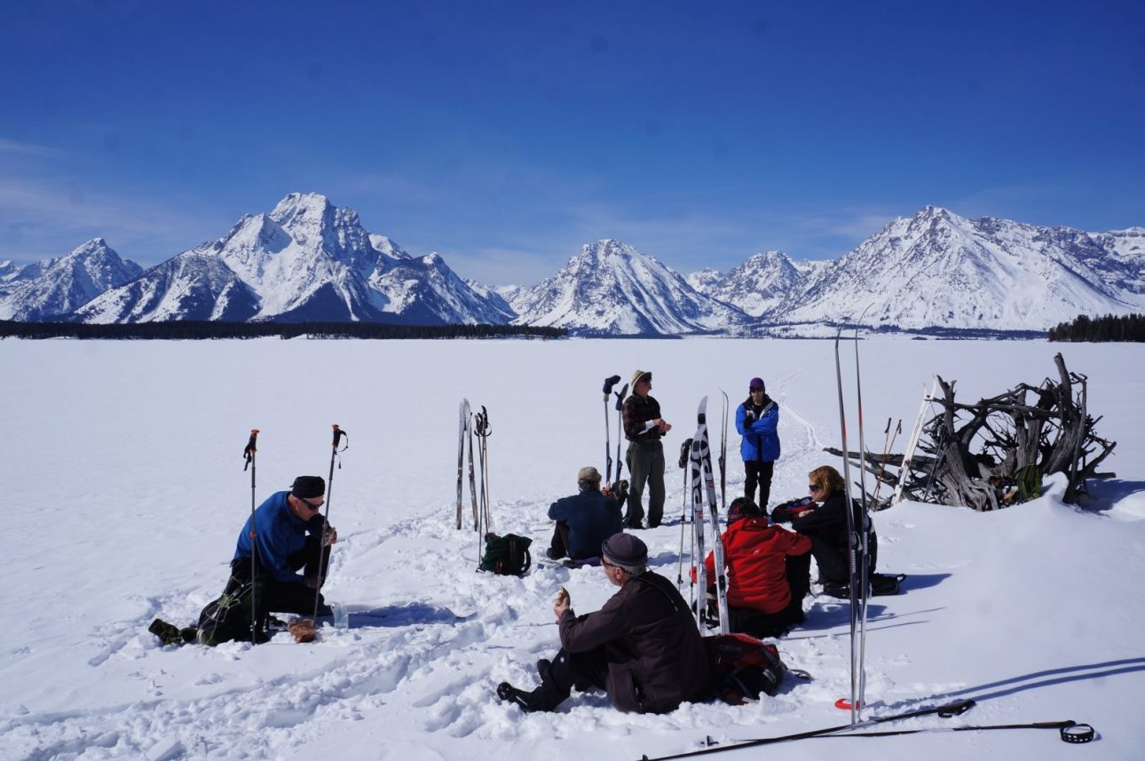 GTNP Ski and snowshoe trip - image of a group taking a break in front of the Grand Teton cathedral mountains