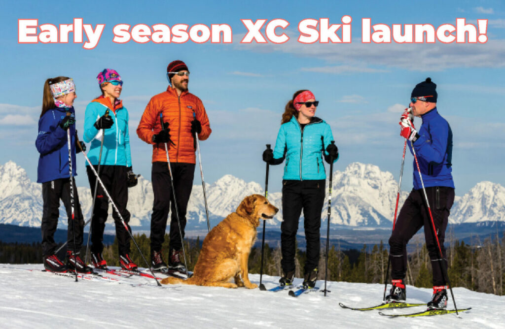 After fall, comes ski season. Five skiiers visiting at the top of a ski hill with a dog.