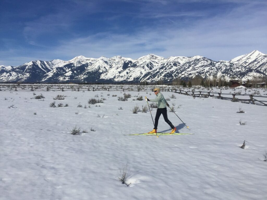 Skier with yellow boots and skis cruises around on an open field in GTNP
