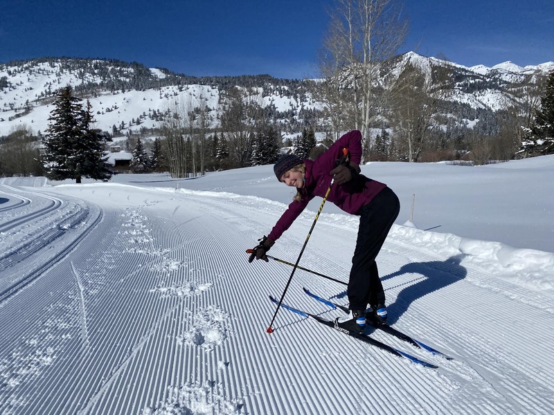 A skier pointing to image of moose tracks on the groomed trail