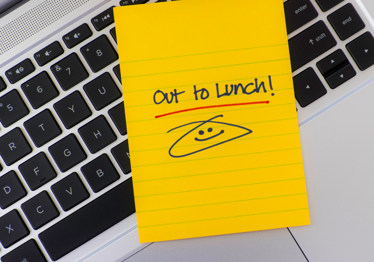a note on top of a computer saying "Out to Lunch" with a smiley face :) 