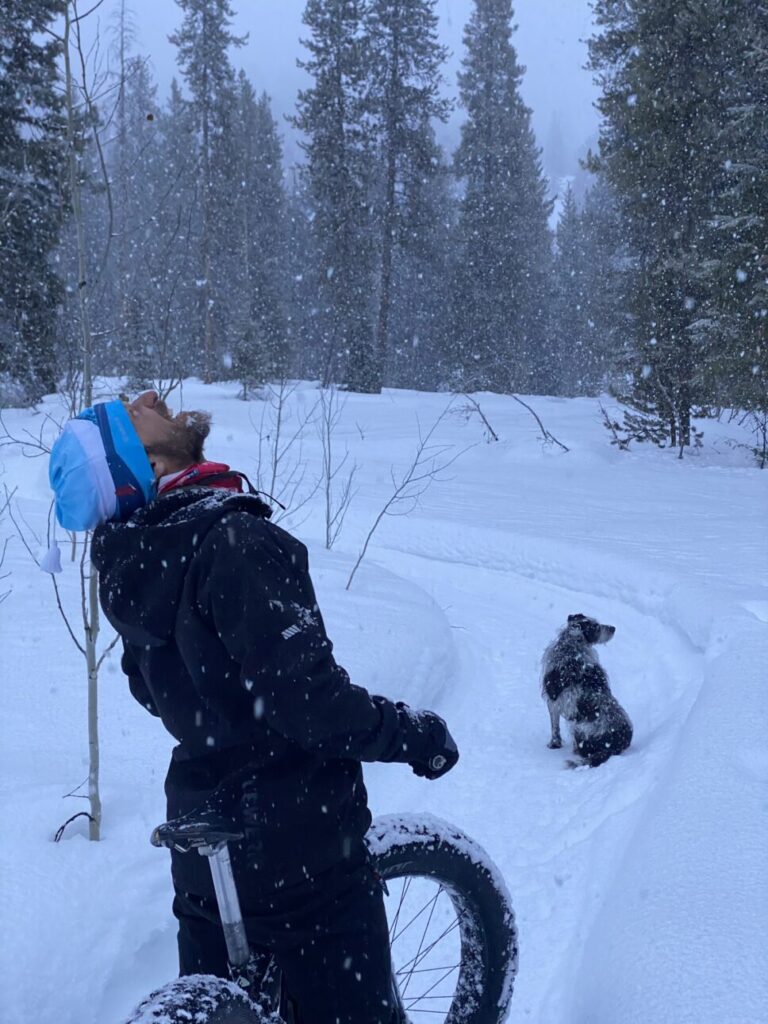 man catching snowflakes, out for a fat bike ride with his dog on the Turpin Meadow trails