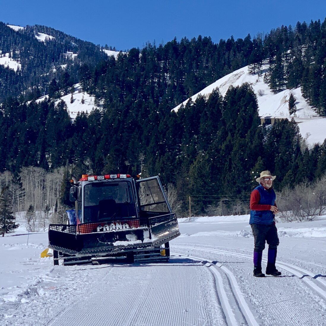 Groomer Steve out on the track with blue skies and flurries