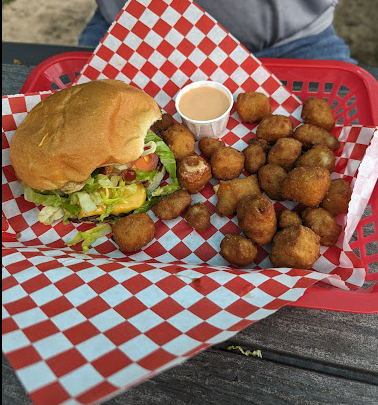 A smash burger and fried cheese curds with a red and white paper liner in a red basket