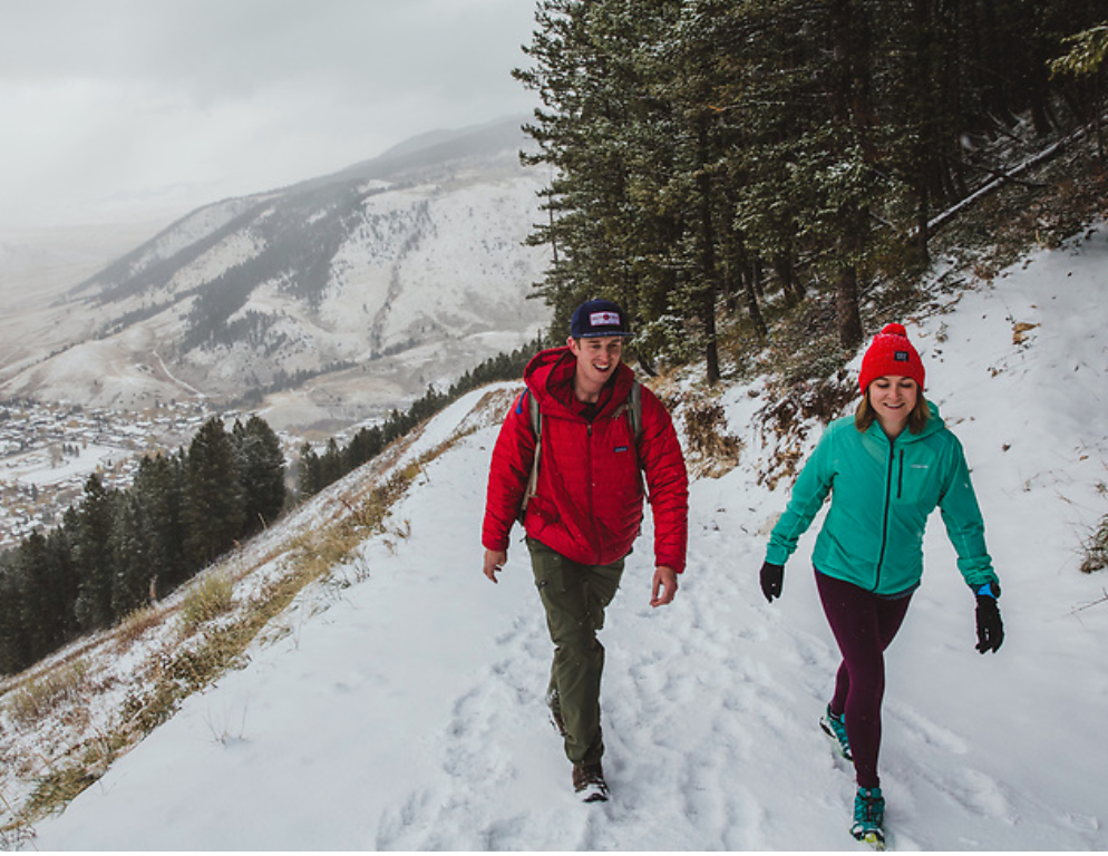 Image of two people walking down a snow covered trail
