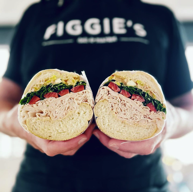 Someone wearing a figgies shirt with a beautiful center cut of a hoagie sandwich 