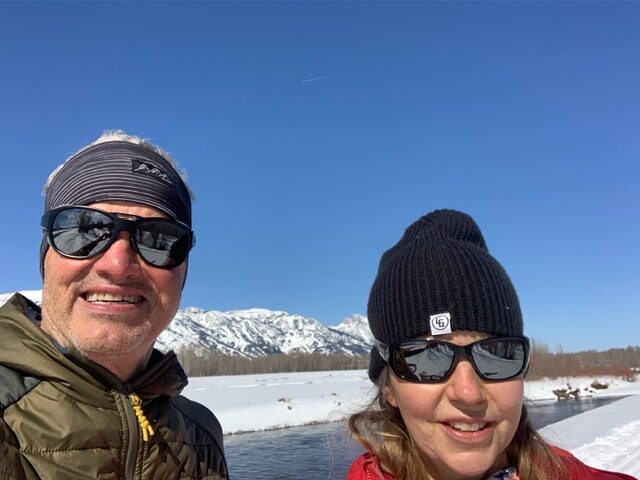 Michael and Trish with snowy mountains and river behind them