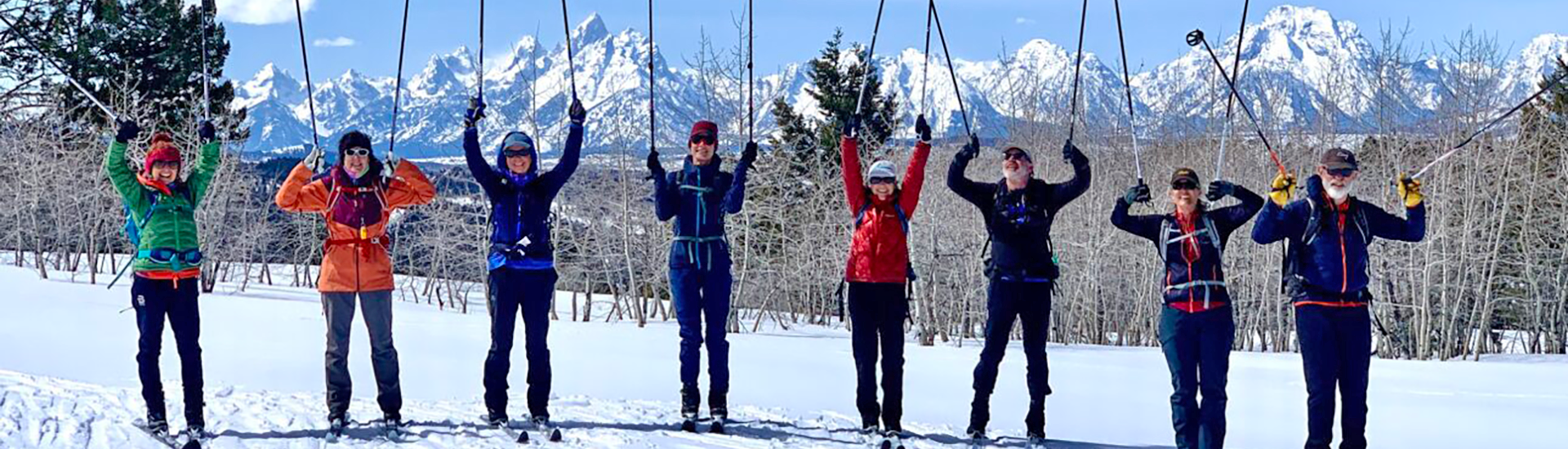 a group of happy nordic skiers with ski poles up in the air at Shadow Mountain, Tetons in background