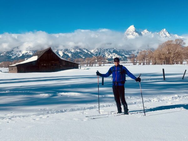 Photo of Frank Brummer in front of old barn and Grand Tetons, outside in winter