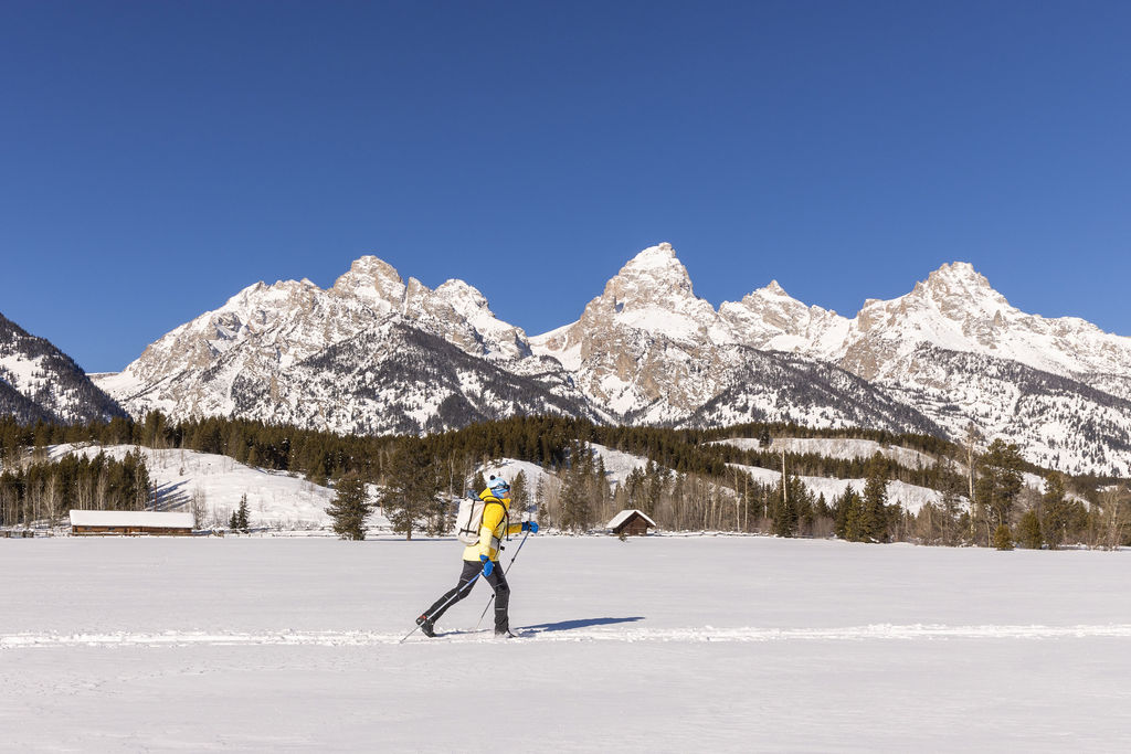 Classic skier striding in front of Tetons on bluebird day